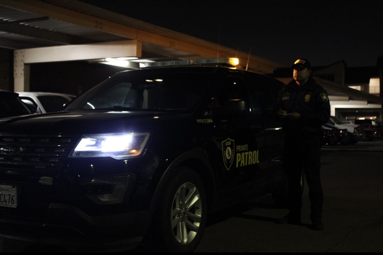 Alcon officer writing notes beside a marked patrol SUV at night